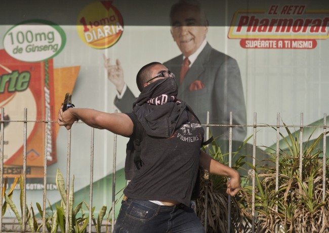 A demonstrator throws a molotov cocktail at Bolivarian National Guards during clashes near Plaza Altamira in Caracas, Venezuela, Sunday, March 16, 2014. Anti-government street protests by Venezuelans fed up with violent crime, shortages of basic items such as flour and cooking oil and high inflation have roiled Venezuela for more than a month.