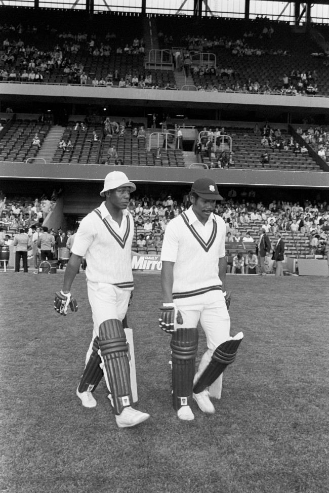 Cricket - Essex v West Indies - Day-Night Floodlit Match - Stamford Bridge Desmond Haynes (l) and Gordon Greenidge (r) of the West Indies walk out to the crease. The floodlit cricket match at Chelsea Football Club's ground, Stamford Bridge, was the first in England, as pioneered by the Packer Circus in Australia. The batsmen wear dark pads and gloves and the bowlers use a white ball. Archive-PA193552-1c Ref #: PA.4836613  