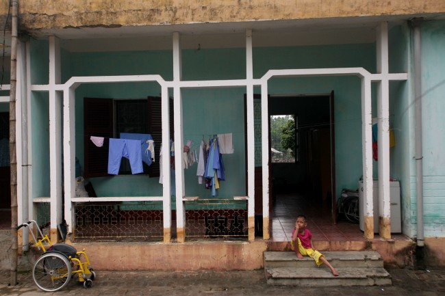 A physically and mentally disabled child sits on the steps of a hospital ward at a "peace village" center in the village of Thuy An, Vietnam, which houses people suffering from illnesses and deformities associated with contact to dioxin in chemical defoliant Agent Orange, in this May 15, 2007, file photo