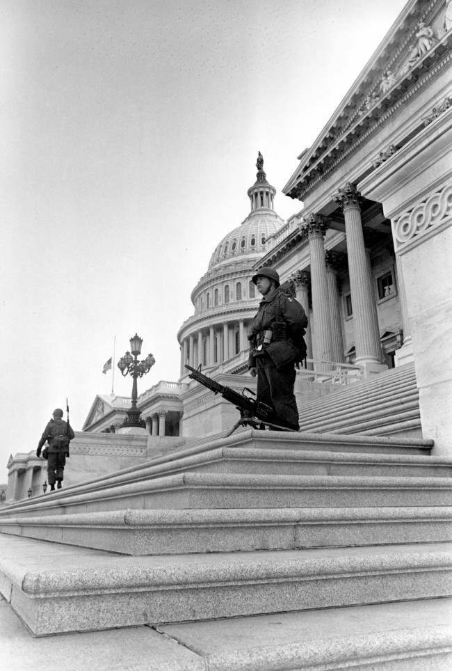 Troops, one with a machine gun, stand guard on the steps of the U.S. Senate wing of the Capitol Building in Washington, D.C., April 5, 1968. Federal troops were called into the nation's capital by order of President Lyndon Johnson during a day of arson and looting following the assassination of Dr. Martin Luther King, Jr. in Memphis, Tenn., April 4. The flag is at half staff in tribute to the civil rights leader.