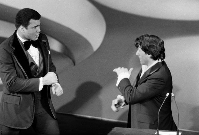 Heavyweight boxing champion Muhammad Ali, left, makes a suprise appearance on the Academy Awards show, accusing actor Sylvester Stallone in jest of stealing "my script" and then sparring with Stallone, who wrote and starred in the boxing film "Rocky," in Los Angeles, Calif., March 28, 1977. Stallone and Ali presented the award for best supporting actress. 
