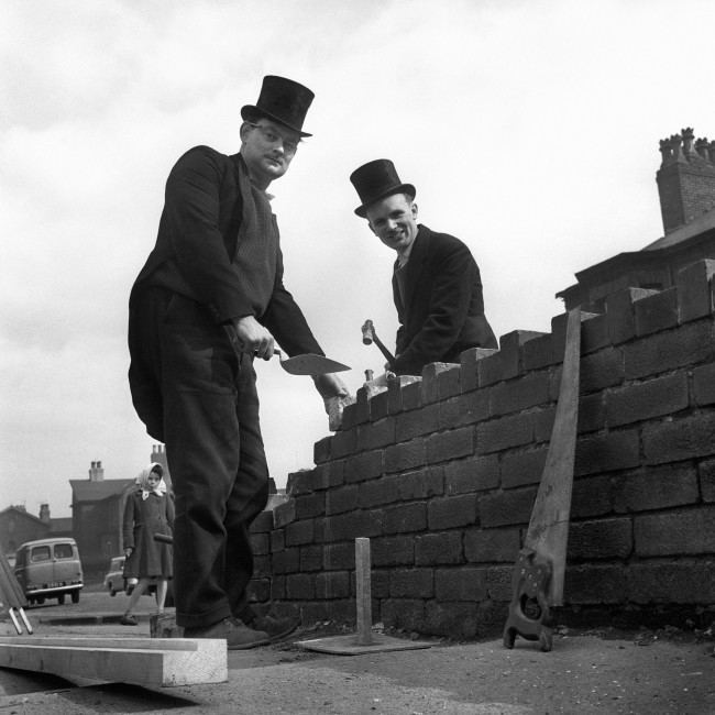 Wearing top hats and tails as they build a wall in Manchester are Malcolm West, 31, of Levenshulme, Manchester (left) and Colin Whittaker, 26, of Edgeley, Stockport, who run their own building business. Because they are 'fed up' with the working man always being associated with cloth caps and overalls, they go to work in morning dress (bought for five shillings) and toppers - and hope that other working men will follow suit.