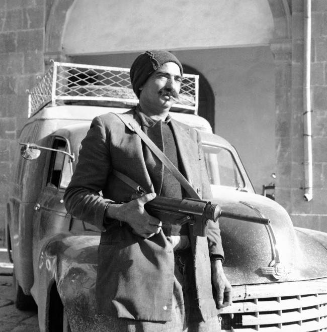 The Greek Cypriot Eoka Organization began handing in arms all over Cyprus, by the evening 613 rifles, guns and sub-machine guns, 17,000 rounds of ammunition, 2,000 bombs and a ton of explosive had been surrendered here, a Greek Cypriot poses with his Gun Outside Kykko monastery, near Nicosia, Cyprus, on March 13, 1959 as he arrived to hand it over to the Cyprus police yesterday.