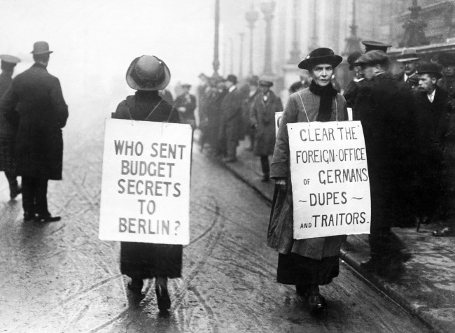 Two patriotic women protest with sandwich boards outside the Reform Club, where a meeting of the Liberal Party was being held. The women allege that there are "Germans, dupes and traitors" in the Foreign Office and that some one sold secrets regarding the annual budget to the Germans. 