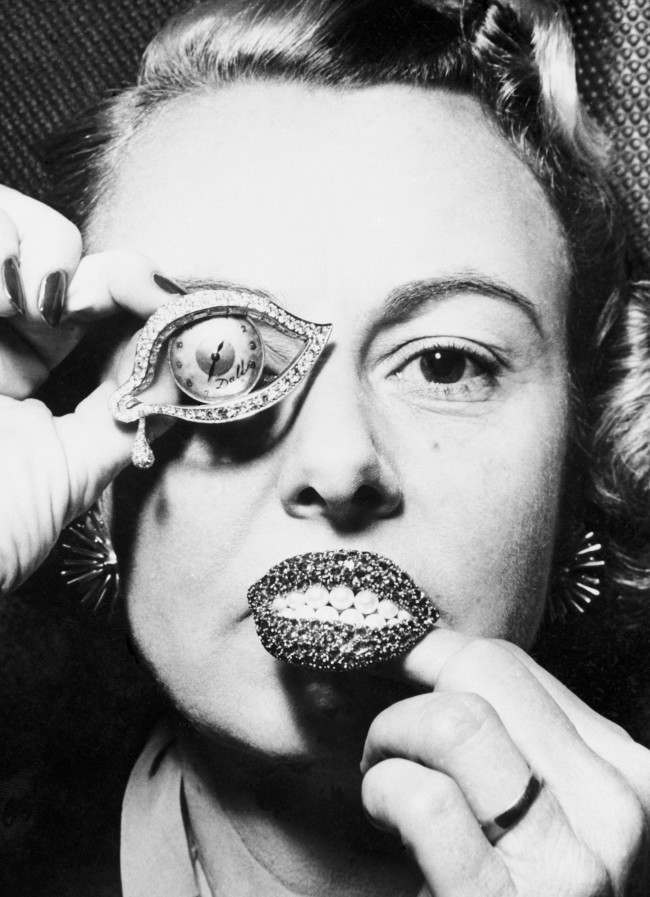 Jewellery by Salvador Dali, a watch in the shape of an eye surrounded by diamonds and rubies, and a brooch of rubies in the shape of lips with pearls as teeth. Date: 08/11/1954 