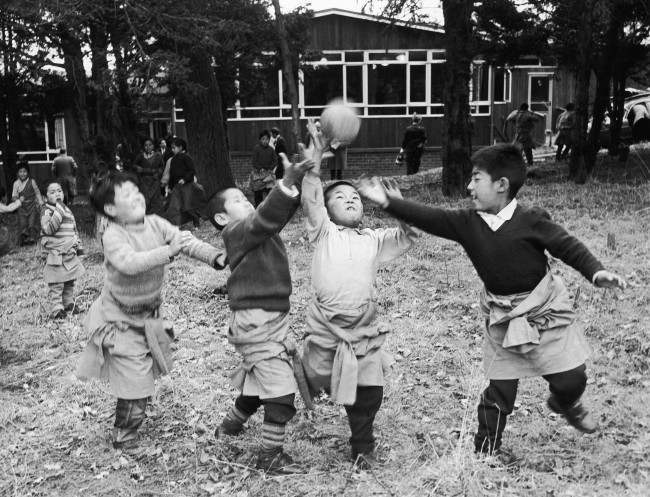 Four young Tibetan boys, some of the 21 Tibetan refugee children now settling in at the Pestalozzi children's village at Sedlescombe, near Battle, Sussex, England, enjoy a game of ball near their cedar wood house in the village on March 7, 1963. The children, who fled from the Chinese in 1956, are making new lives in Britain, after being specially nominated to come to this country by the Dalai Lama himself. He hopes they will be trained as doctors, teachers or in other skilled professions so they way eventually go back to their own land and help others less fortunate than themselves. 