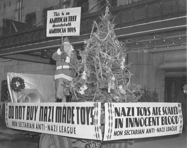 A Santa Claus on wheels appeared in front of a store in New York City on Dec. 6, 1938. The Santa bares signs urging the boycotting of Nazi Manufactured toys. A Christmas tree decorated with American toys shared the spotlight. 