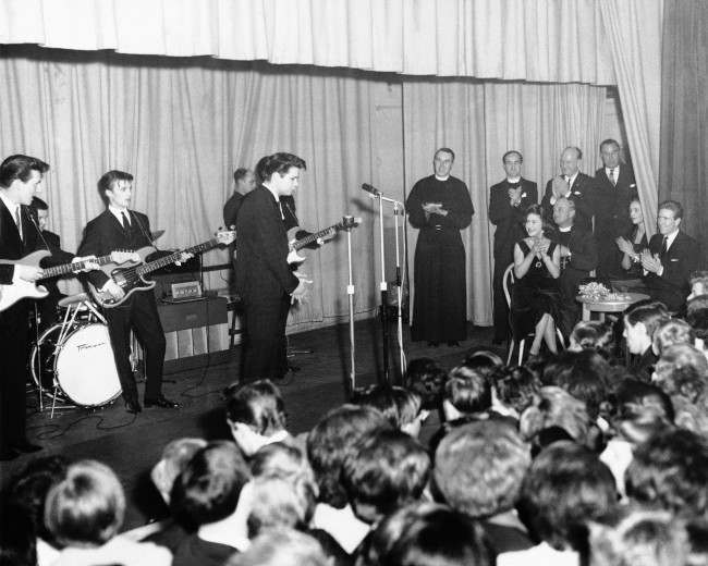Princess Margaret and her husband, Lord Snowdon, applaud from their table at right, as pop singer Cliff Richard sings at a youth club in London's Hackney district, March 22, 1962. The princess was the center of a stamping, whistling group of teenagers. 