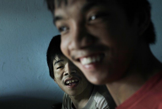 In this photo taken on Oct. 5, 2009, Tran Van Lam, left, and Tran van Hoang sit inside their family home in the village of Cam Tuyen, Vietnam. The two men were born with profound physical and mental disabilities that the family, and local officials, say were caused by their parents' exposure to the chemical dioxin in the defoliant Agent Orange.