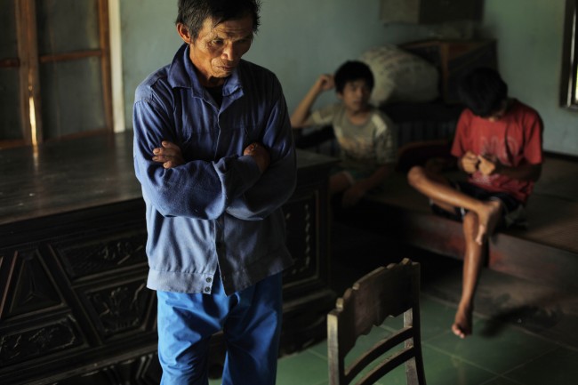 In this photo taken on Oct. 5, 2009, Tran Van Tram, 60, stands inside his home in the village of Cam Tuyen, Vietnam. Tran Van Tram and his wife have raised four children with profound physical and mental disabilities that the family, and local officials say, were caused by his parents' exposure to the chemical dioxin in the defoliant Agent Orange.