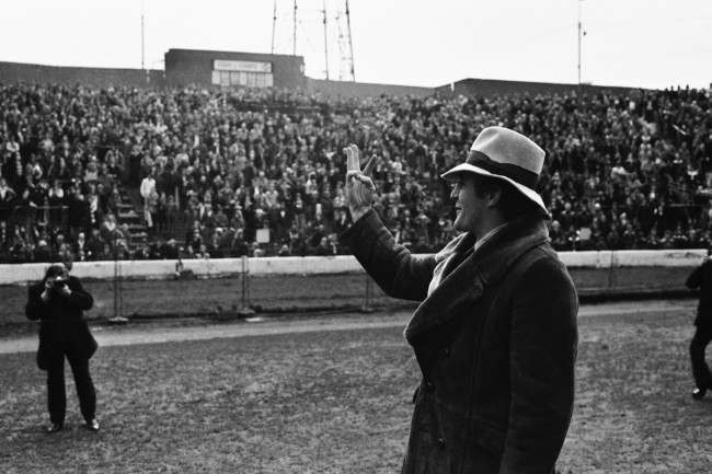 Manager of Crystal Palace Football Club Malcolm Allison wearing a hat, indicates his team's three goals to the fans at Stamford Bridge, London on Feb 15, 1976. Palace beat Chelsea 3-2 in the FA Cup match. (AP Photo/Peter Kemp) Ref #: PA.9639056  Date: 15/02/1976 