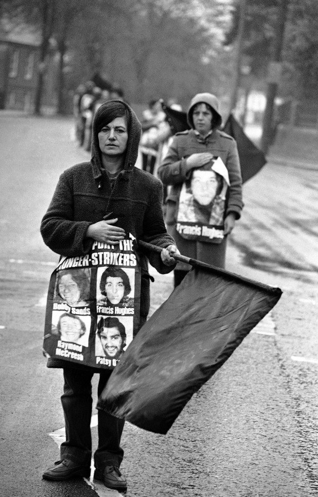 Protestors supporting the H-block protest, wave black flags of mourning for hunger striker Bobby Sands, as they stand in the center of BelfastÂs Falls Road on May 5, 1981. The protestors were mourning the death of Sands, who died early Tuesday, at the start of his 66th day of hunger strike in Northern IrelandÂs Maze Prison. (AP Photo/David Caulkin) Ref #: PA.10427033  Date: 05/05/1981