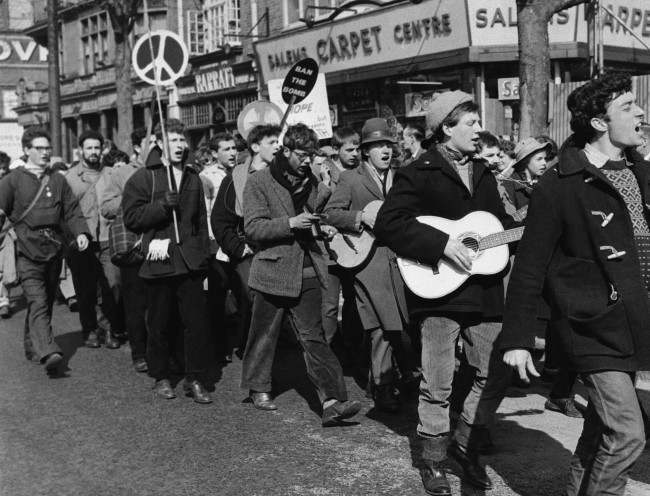 Guitar strumming youths and banner bearers march into London on April 18, 1960 in the 20,000 strong procession of anti a bomb demonstrators protesting against the manufacture of nuclear weapons? The procession is heading for Trafalgar Square London, where huge anti bomb rally is scheduled. (AP Photo) Ref #: PA.10742786  Date: 18/04/1960 