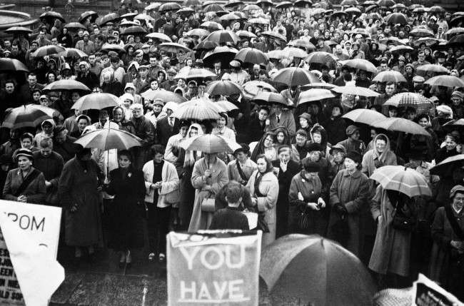 An huge crowd, mostly women sheltered under their umbrellas in Trafalgar square, London on May 12, 1957, at a mass meeting of the national council for the abolition of nuclear weapon tests. The rally was organized as a womenÂs protest march against H-bomb tests from Hyde Park to Trafalgar square. (AP Photo) Ref #: PA.10742792  Date: 12/05/1957