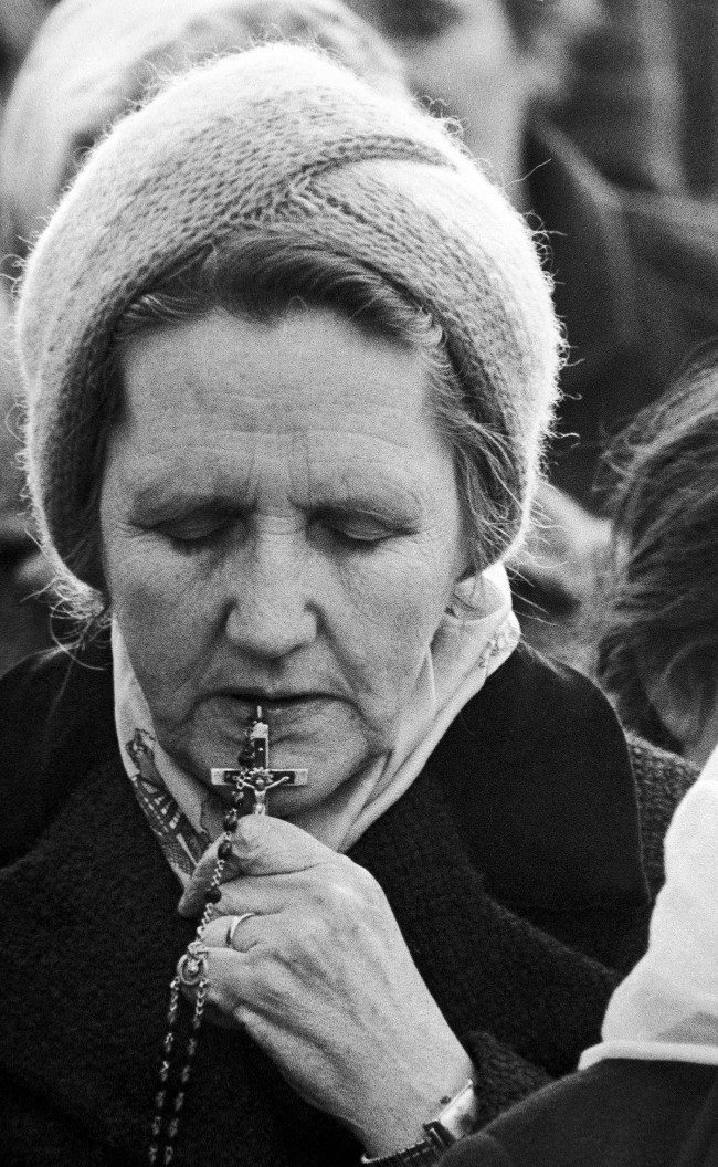 An unidentified woman holds her rosary to her lips, during a prayer service for Bobby Sands and his fellow IRA hunger strikers, in a Catholic area of Belfast on Friday, May 1, 1981. Sands is now in the 62nd day of his hunger strike at Northern IrelandÂs Maze prison. (AP Photo/David Caulkin) Ref #: PA.11670696  Date: 26/04/1981