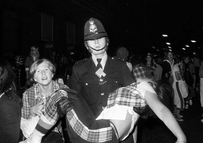 A policeman carries a young female fan outside the New Victoria Theatre in London. PA/PA Archive/Press Association Images