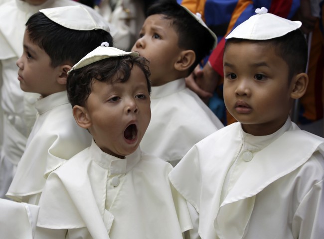 A boy dressed as a Pope, yawns as he prepares to join a parade in celebration of the canonization or the elevation to sainthood in the Vatican of Roman Catholic Pope John Paul II and Pope John XXIII Sunday, April 27, 2014, at suburban Quezon city, northeast of Manila, Philippines.