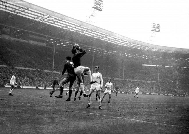 Leeds United goalkeeper Gary Sprake (c) claims a cross under pressure from Liverpool's Ian St John (l), watched by teammate Jack Charlton (r)