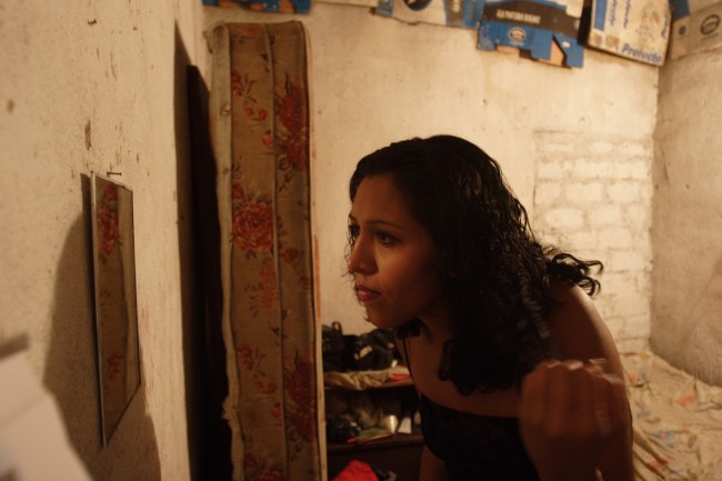 A prostitute from El Salvador who identifies herself as "La Flaca," or "Skinny," checks her makeup 