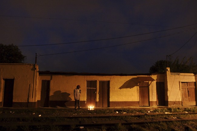 A man stands next to burning candles that were lit in homage to Silvia Yolanda Martinez, 28, who was shot in the back five times in broad daylight for allegedly refusing to pay the local tax that gangs charge so that she can work as a prostitute in what is known as La Linea, or The Strip where dozens of women work as prostitutes in Guatemala City late night Friday, June 22, 2007