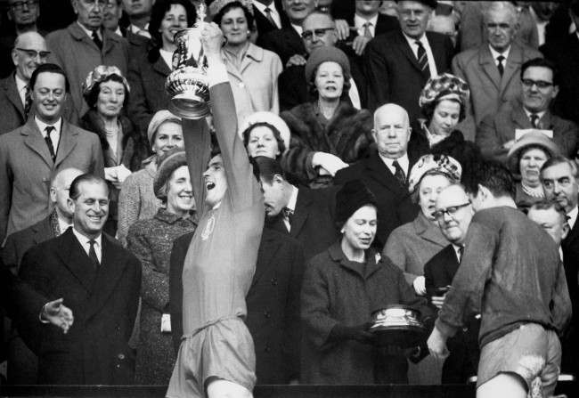 Liverpool captain Ron Yeats (second l) lifts the FA Cup as teammate Tommy Lawrence (r) collects the base of the trophy from HM Queen Elizabeth II (second r) 