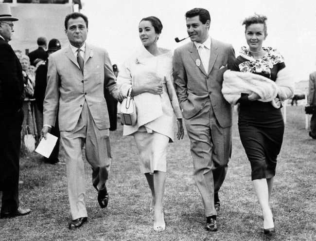 A quartette of film folk stroll along the turf on Epsom Downs, on June 5, 1957 during the 178th Derby Stakes in England. Left to right, Mike Todd and his wife Elizabeth Taylor, singer Eddie Fisher, and his wife actress Debbie Reynolds. (AP Photo) Ref #: PA.7566521  Date: 05/06/1957 