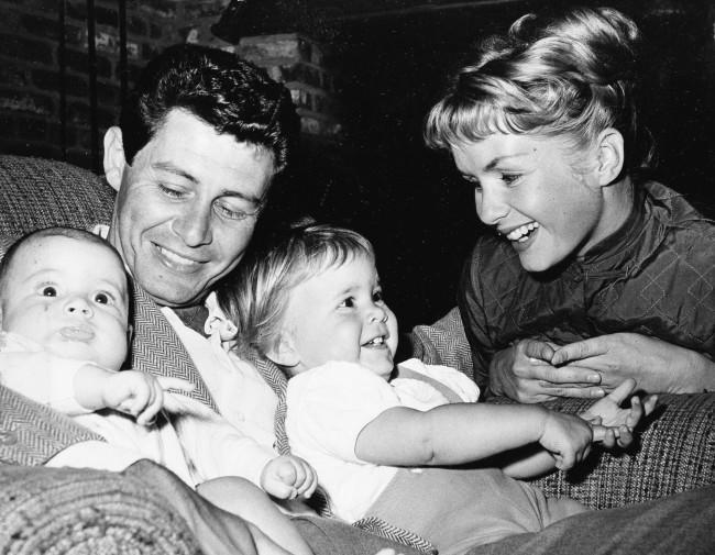 Singer Eddie Fisher, out of the hospital in time for Father's Day, cuddles his two youngsters four-month old Todd, left, and 19-month-old Carrie. Looking on is their equally famous mother, actress Debbie Reynolds. Eddie spent ten days in the hospital following an appendix flare-up. (AP Photo) Ref #: PA.8554988  Date: 14/06/1958 