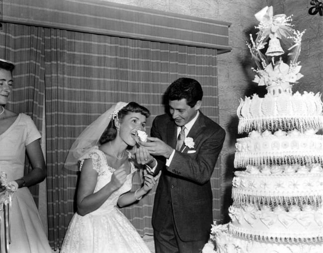 Singer Eddie Fisher, 26, feeds a piece of wedding cake to his bride, actress Debbie Reynolds, 23, following their marriage at Grossinger, N.Y., on Sept. 26, 1955. (AP Photo/Marty Lederhandler) Ref #: PA.8692524  Date: 26/09/1955 