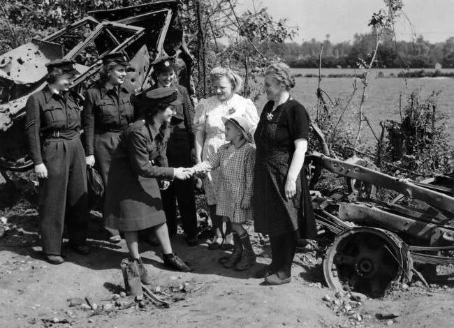 Members of the first WAAF contingent to arrived being greeted by French people in Normandy on August 6, 1944. In the back ground is a burnt-out German motor vehicle. Section Officer J. Bradbury of Hale, Cheshire is shaking hands with the child; looking on from left to right are Cpl. J.J. Disney of Denton, Norfolk, L.A.C.J. Davis, of Dalson, London E.8. and Sgt. M.D. Easson of Edinburgh. (AP Photo)