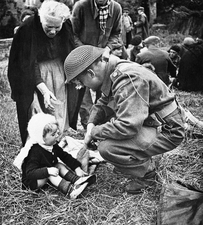A Canadian soldier, serving with the British forces in Normandy, France, strikes up an acquaintance with a little French girl on Sept. 7, 1944, one of a group of refugees that were fed by the liberating armies. The feeding arrangements were organized by the Civil Affairs. (AP Photo) 
