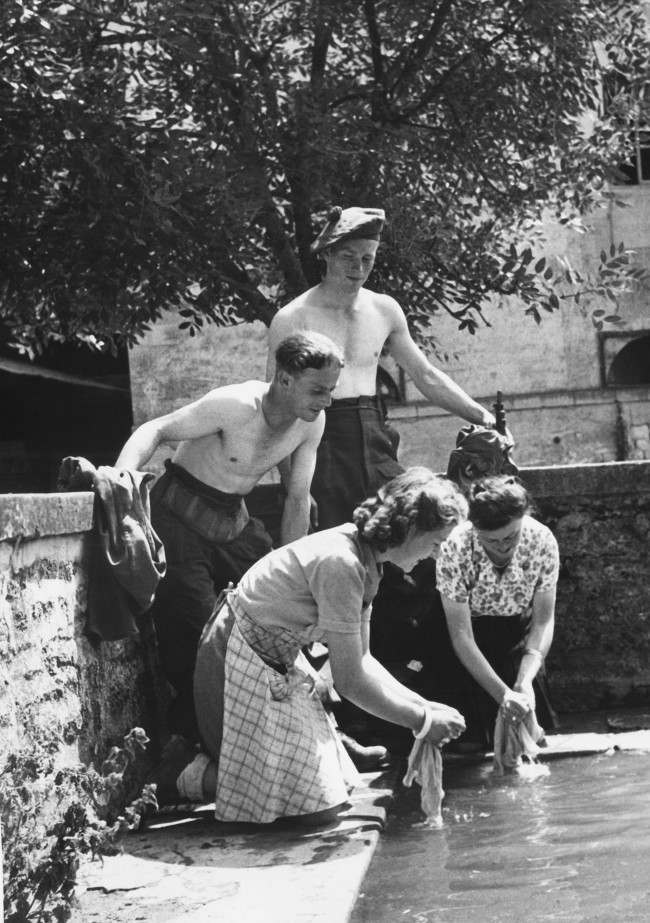 Two British soldiers taking part in the liberation of France from the Germans are rewarded by Frenchwomen, of a Normandy farm, by having their laundry washed for them in France on July 15, 1944. (AP Photo)