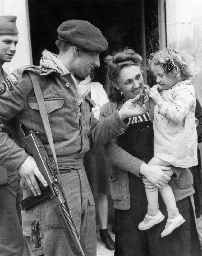 French villagers welcomed members of a French Commando who landed in Normandy in Amfreville, North of Ranville on June 17, 1944. Chester Wilmot, BBC commentator was also there at the time. A French Commando greeting a little girl who had been brought out to see him. (AP Photo)