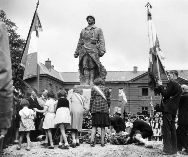 Bastille Day celebrations in the little Normandy town of Isigny on July 19, 1944 took the form of services at the townÂs War Memorial. French children pass in turn to lay their tributes to war dead at the War Memorial during the services. (AP Photo/Bert Brandt)