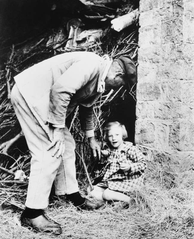 A bright-eyed little French girl is persuaded to leave the spot, behind a pile of branches, where she made her home when the Allies swept into her community in Normandy on June 15, 1944. (AP Photo)