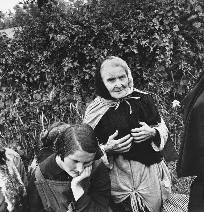 An aged French woman, who fled from her home when the allies launched their attack on the Normandy peninsula of France, waits at a roadside with other refugees for the tide of war to pass so they can return to their homes on June 24, 1944. (AP Photo) 