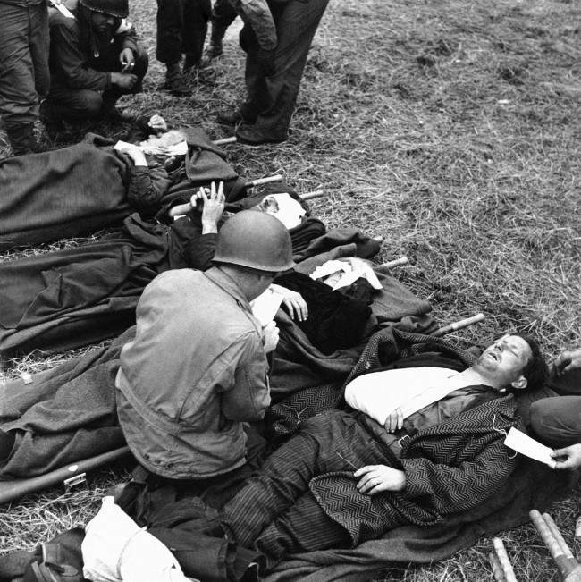 rench civilians, wounded during the Normandy battles on June 19, 1944, lie on stretchers on the ground behind the lines, where they are treated by U.S. Army medical corpsmen. (AP Photo)