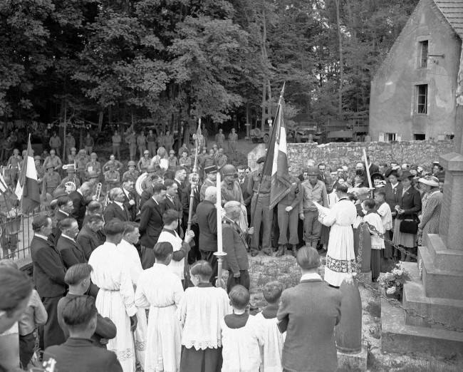 U.S. Army bandsmen (left, background), attend with French civilians the Bastille Day services held in a church cemetery in the liberated village of Castilly in Normandy, France on July 19, 1944. (AP Photo/Harry Harris)