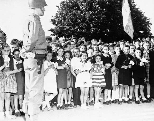 French children of the Normandy town of Grandcamp, France, some carrying American flags and others dressed in patriotic costumes, join American occupation troops in celebrating the American Independence Day on July 4, 1944. Many residents turned out for the ceremonies in the village, which was the first to be liberated by the invading allied forces. (AP Photo)