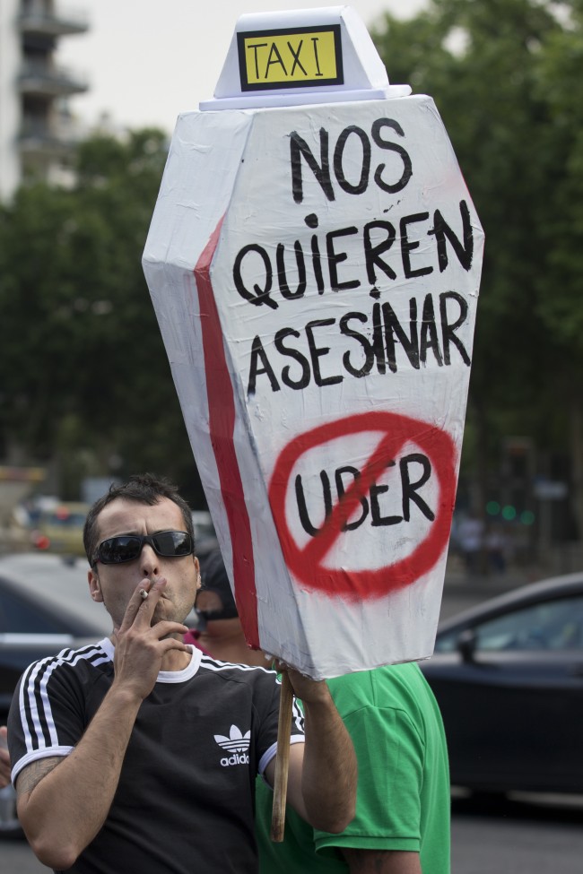 A demonstrator carries a mock coffin with a message reading 'They want to kill us - Uber' during a 24 hour taxi strike and protest in Madrid, Spain, Wednesday, June 11, 2014. 