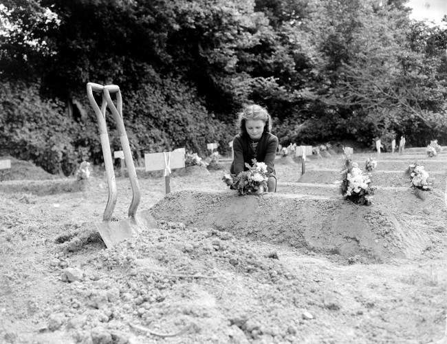 A French girl places flowers over the freshly-dug grave of an American Airborne trooper as a token of appreciation of arrival of Allied liberators on the northern coast of France, June 12, 1944. The trooper was killed when his glider landed in the Normandy area of France in World War II. (AP Photo/Peter J. Carroll)