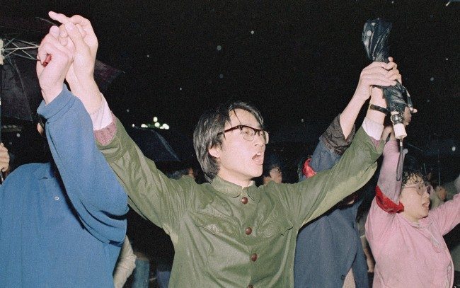 University students hold hands as they sing the Chinese National Anthem during a protest, April 21, 1989 in Beijing's Tiananmen Square. (AP Photo/Mark Avery)