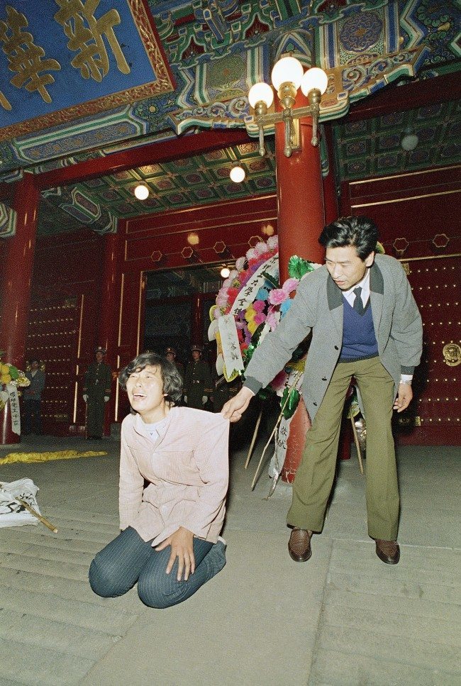 A Chinese security guard gently tries to move a weeping young woman away from the ornate entrance to the Chinese Communist Party headquarters, Zhongnanhai, early on Wednesday, April 19, 1989 in Beijing. University students converged on Zhongnanhai after demonstrating in Tiananmen Square all day on Tuesday. The students tried to storm the gate, but were fought back by Chinese security. (AP Photo/Mark Avery)