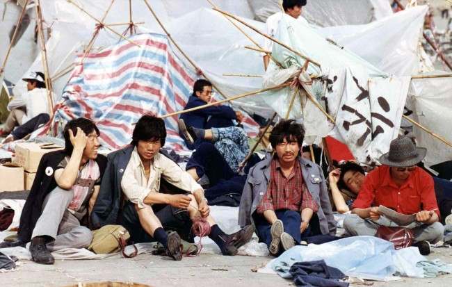 A group of students rest before their tattered tents in Tiananmen Square, Beijing, on May 27, 1989, where thousands of students continue their sit-in protest to press the government for political reforms. (AP Photo/Staff/Widener)