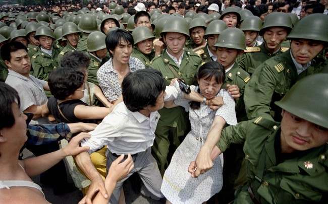 A young woman is caught between civilians and Chinese soldiers, who were trying to remove her from an assembly near the Great Hall of the People in Beijing, June 3, 1989. Pro-democracy protesters had been occupying Tiananmen Square for weeks. (AP Photo/Jeff Widener) 