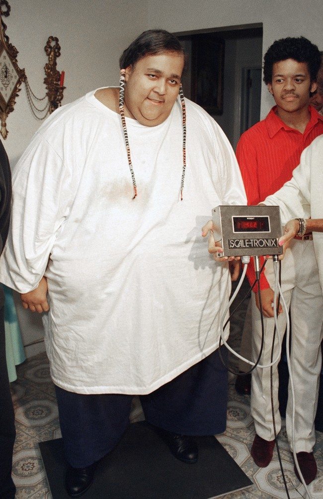 Walter Hudson smiles in New York, July 14, 1988, as he stands on a scale that shows that he now weighs only 562 pounds. 