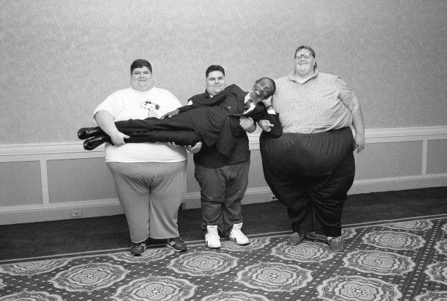 Comedian turned nutritionist Dick Gregory gets a heavy-handed lift, left to right: 526-pound Ron Miller, of Marion, Ind., 375-pound Lou Barone, Elmont, New York, and 750-pound Mike Parteleno, Struthers, Ohio, June 7, 1988 in New York. Gregory has assembled a group of 13 obese people, whose total weight is nearly three tons, in a nutrition program aimed at helping them lose weight.