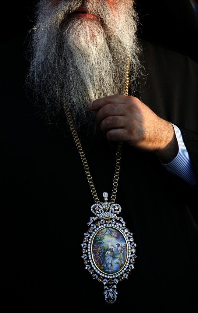 In this Tuesday, June 26, 2012 photo a Russian priest strokes his beard while waiting for the arrival of Russian President Vladimir Putin, not shown, to inaugurate the Russian guesthouse in North Shuna, Jordan. (AP photo/Mohammad Hannon)