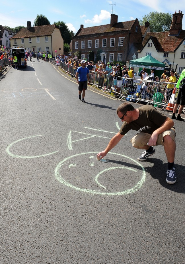 Cycling fans chalk on the road as they wait in the village of Finchingfield in north Essex