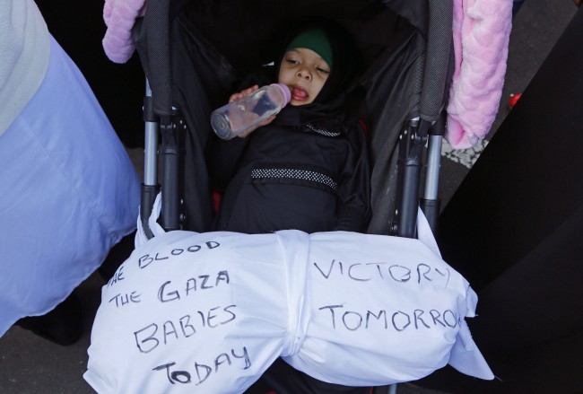 A baby of a Palestinian supporter, with a of cloth, with a slogan on it attends a rally against the Israeli occupation of the Palestinian territories in Cape Town, South Africa, Saturday, Aug. 9, 2014.