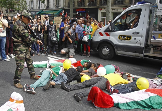 A demonstrator pretends to shoot at children with a Kalachnikov model, as pro-Palestinian demonstrators chanting anti-Israeli slogans, in a street of Paris, Saturday, Aug. 9, 2014, in support of Hamas and against the Israeli operations in the Gaza strip. Israeli airstrikes struck more than 20 targets Saturday in the Gaza Strip and killed a senior Hamas member, as militant rocket fire continued following the collapse of a three-day truce aimed at ending the war between Israel and Hamas. (AP Photo/Remy de la Mauviniere)